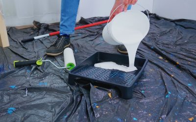 Handyman pouring white paint for home renovation. Couple in apartment flat, repair and makeover