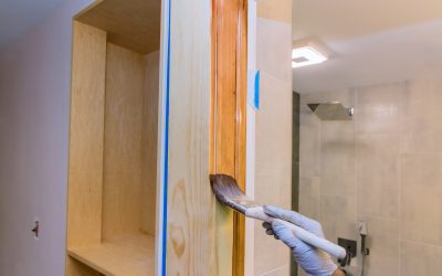 Contractor painter varnish for a brush painting new molding trim wooden front door using paintbrush varnish with gloves