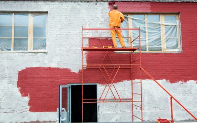Man painting a brick wall in red