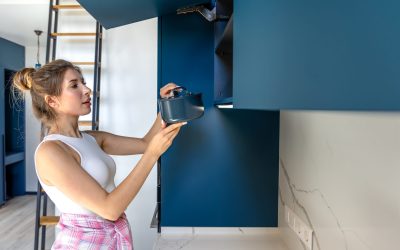 A woman puts a pot into a cabinet in a modern blue kitchen. A minimalist and clean space that reflects care and routine. SSUCv3H4sIAAAAAAAAA41Py46DMAz8F59B4rG0wK9UPeThUqtAqsTZaoXy7+tQqr1uDtaMJ/aMNyALI2Cle6xNVZ6bpi3r+laVg/o6l9XtpFE3th4ahAKsYoSxbtuh7wcp3anrKnkFaBXIwLgBzXMM7BWTW2EUxeNq0e8QLbHzpGZhqYDAimPAIGPCjOyeRN35Z99ly30JKOYh6gxS8c/etQA14Wp+8v6Ug8yodruLSI8Xo18Ob8f3HDHDpydD63RkklPc8sar4zy7O7AzD7LH8PuMO0nXZy+Iz9kpi/aQo16I+UM9fhO+/n6nlH4BTFCvTIQBAAA=